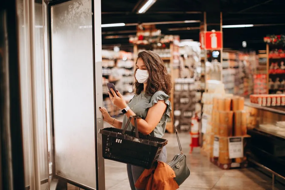 Shopper checking a list on her phone in a supermarket aisle